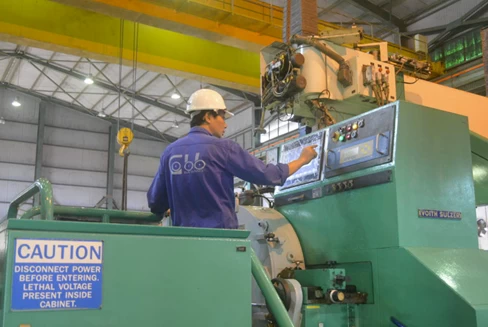 Kỹ thuật viên thao tác trên bảng điều khiển của máy xeo giấy đang vận hành